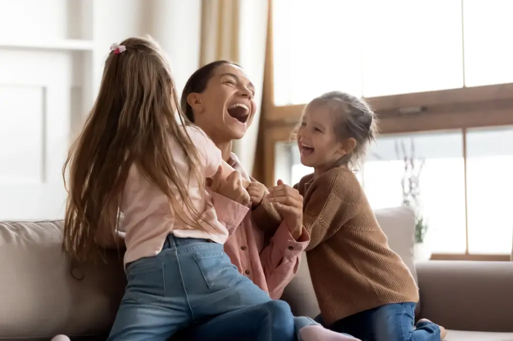 A mom playing with her two kids in the living room.