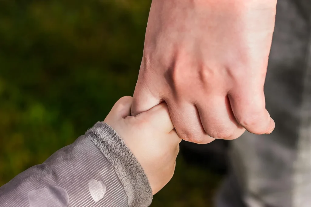 A close up of a father holding a child's hand.