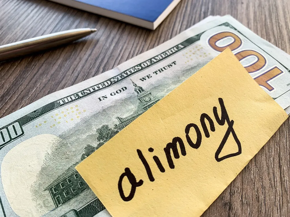 A 100 dollar bill and a post it note that says alimony.