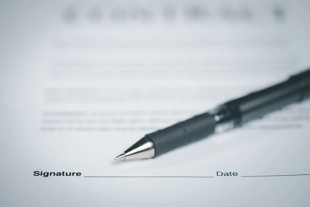 A black pen and a document with a blank signature line.