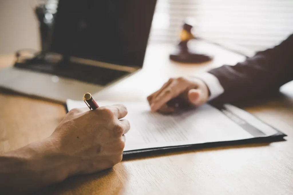An attorney pointing to a place to sign on a piece of paper.