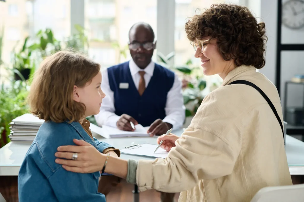 A woman smiling at her child with an attorney behind them.