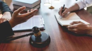 Close-up of a meeting between two professionals, with a gavel, legal documents, and one person taking notes, representing Houston appeals attorneys handling commercial litigation cases.