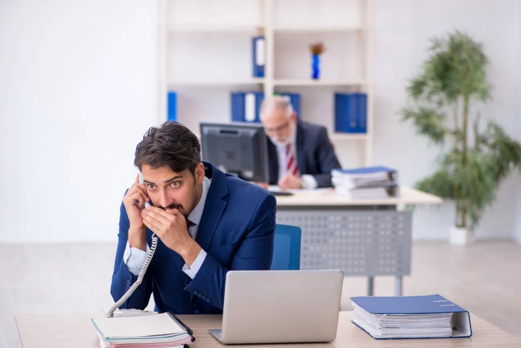 Concerned businessman speaking secretly on the phone in an office, symbolizing the sensitive nature of trade secrets and noncompete litigation.